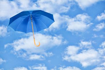 A Mary Poppins umbrella floating in a blue sky with clouds