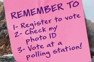 A post it note that says 'remember to register to vote, check my photo ID, vote at a polling station'