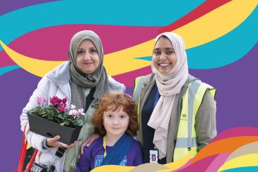 A purple banner with yellow blue and red waves rippled across from the bottom left to top right, with three people standing on the right hand side, one child and two young women wearing hijabs.