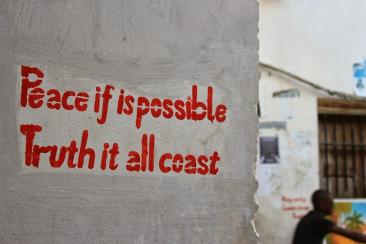 Colour photo of red text on grey concrete wall: peace if is possible truth it all coast