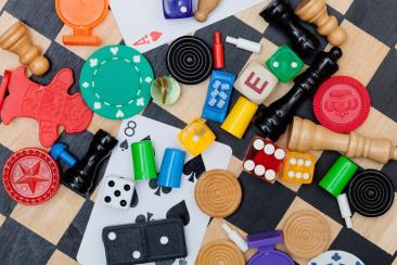 an image of random games pieces such as dice, chess board and cards. 