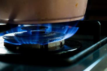 A gas hob, with a bright blue flame and a saucepan on top of it