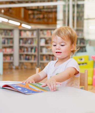 A young child reading a book in a library