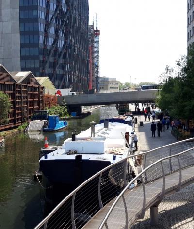 The canal in Paddington with a barge on the water and sheds and buildings on either side