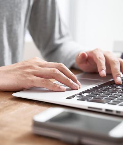 Colour photo of person typing on a laptop