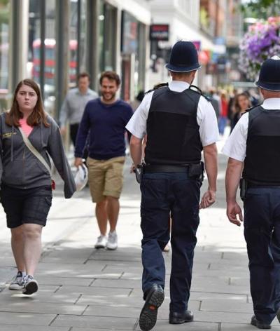 Colour photo of two police officers walking down a high street