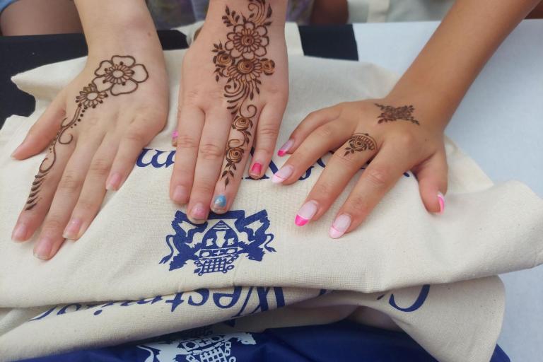 Three hands with henna decorations on them on top of westminster city council branded tote bag