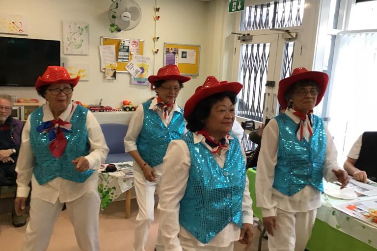 Ladies wearing blue glittery waistcoats and read glittery hats and dancing