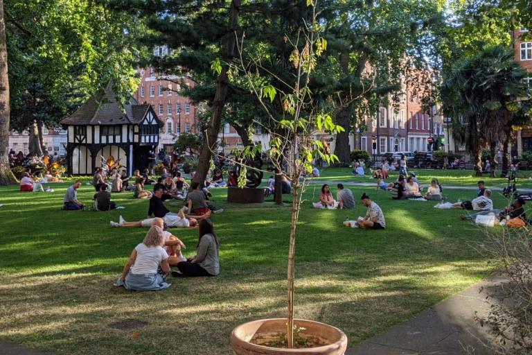 Soho square ona  sunny day with lots of people sitting on the grass