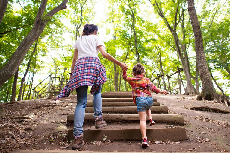 Woman and little girl climbing wooden steps of a mountain path