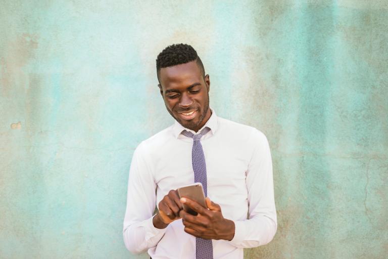 Young man wearing a shirt and a tie and looking at his mobile phone
