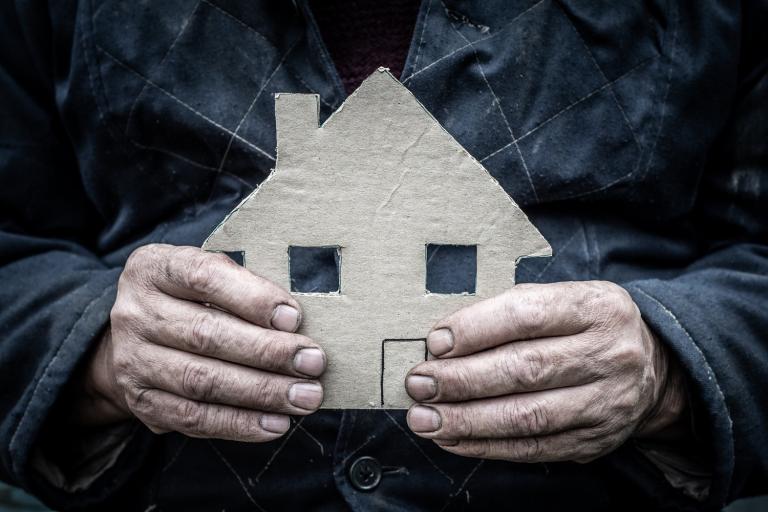 A close up of a man's hands holding a cardboard house