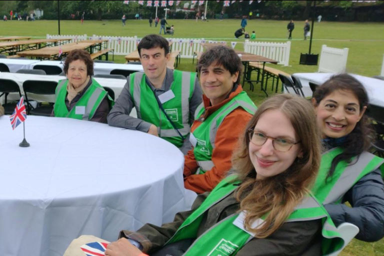 A group of westminster connects volunteers sat around a round white table in a park before an event