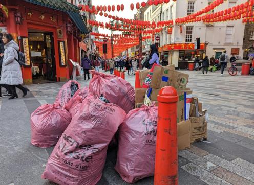 Some fly-tipping of bin bags and cardboard boxes around a bollard in Chinatown