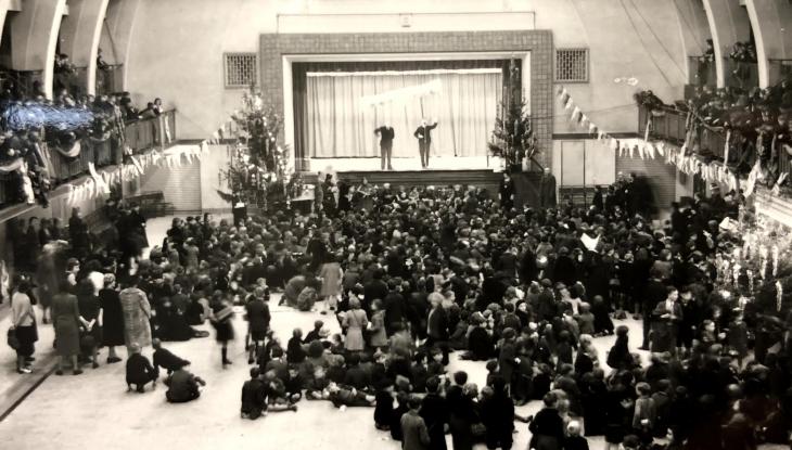 A black and white photo of a few hundred school children watching a play at seymour leisure centre