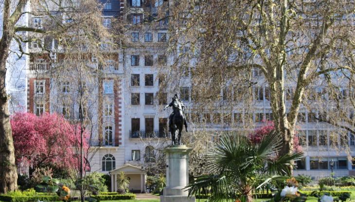 A wide shot of Saint James's Square with lots of greenery and a statue of William the third on horseback in the centre