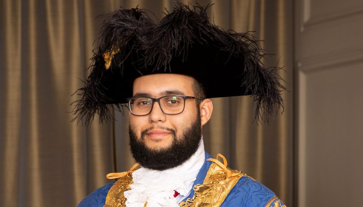 The Lord Mayor of Westminster, Councillor Hamza Taouzzale wearing the traditional blue and gold robes, black feathered cap, and gold ceremonial chain 